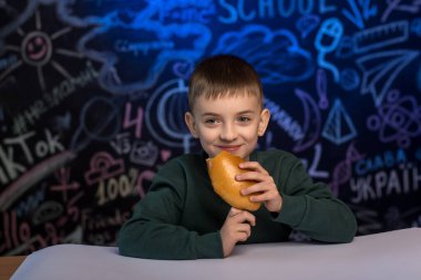 Masasında yemek yiyen mutlu okul çocuğu. Etrafı renkli karalamalarla çevrili. Okul ortamında sağlıklı beslenme ve öğrenmeyi teşvik etmek için mükemmel.