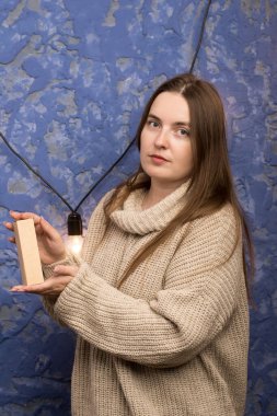 A box held by hands in front of a blue textured wall with a string of lights. Ideal for stock photos featuring home decor, gift packaging, and intimate, cozy themes. clipart