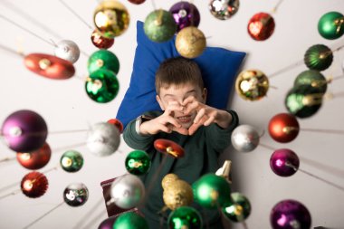 Top view of a happy child surrounded by sparkling Christmas decorations. Captures the magic and innocence of the holiday season. clipart