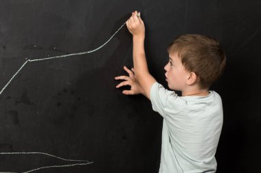 A back view of a child drawing with pink chalk on a blackboard, highlighting the importance of creativity in early childhood education. clipart