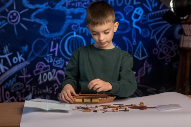 Boy working on a ship model project with a creative classroom backdrop. A perfect image for education, creativity, and school-related content. clipart