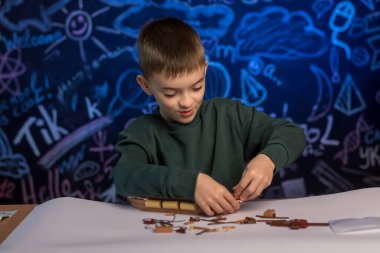 Yaratıcı bir sınıfta karatahta geçmişi olan bir gemi modeli inşa eden neşeli bir çocuk. Eğitim, yaratıcılık ve pratik öğrenme kavramları için mükemmel..