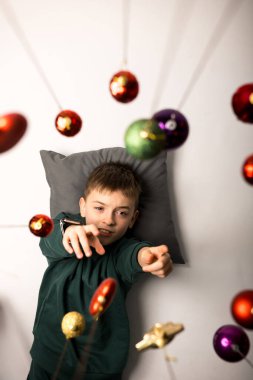 Parlak Noel mücevherleriyle çevrili şirin bir çocuk, neşeli atmosferin tadını çıkarıyor. Eğlence, çocukluk ve mevsimsel kutlamalar için mükemmel bir tema..