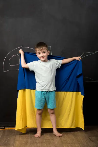 Ukrayna bayrağını gururla taşıyan bir çocuk ulusal kimlik ve gururu simgeliyor. Tahtaya tebeşirle çizilmiş bir eğitim ortamında yakalanmış.