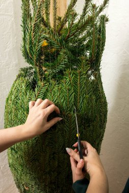 Yetişkinlerin yardımıyla doğal bir Noel ağacından ağ kesen bir çocuğun yakın çekimi. Aile geleneklerini gözler önüne seren detaylı bir festival sahnesi