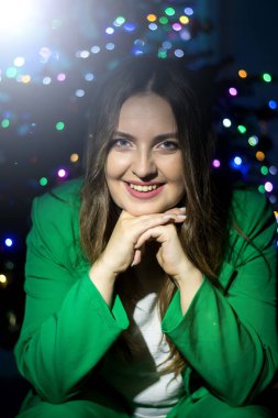 Cheerful portrait of a young woman in front of vibrant Christmas lights. Perfect for seasonal advertising and digital greetings. clipart