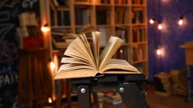 Sayfaları çevirerek, loş bir kütüphane ortamında yakalanan açık bir kitap. Öğrenim, eğitim, bilgi veya hikaye anlatma ilhamı için idealdir.