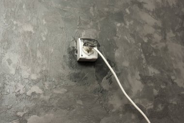 Mikro betondan yapılmış minimalist bir duvar modern bir elektrik prizi ve kabloyla. Endüstriyel tasarım basitlik ve işlevselliği vurguluyor