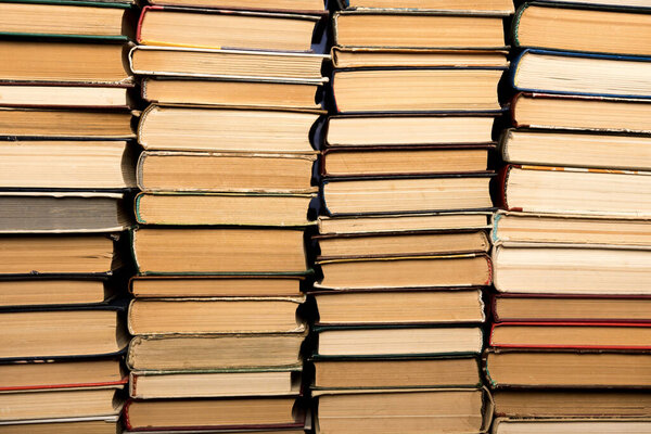 Ряды винтажных книг плотно сложены вместе, демонстрируя свои шипы и изношенные текстуры. Вечный символ знаний, образования и литературной истории.