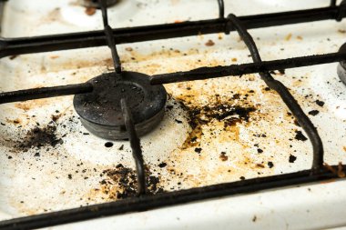 Kirli ve kirli yemek lekeleri olan dağınık bir gaz ocağının üst görüntüsü, dağınık bir mutfak ortamını betimliyor.