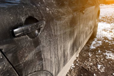 Çamur ve çamurla kaplı bir araba kapısının detaylı bir görüntüsü. Kış havasının araçlar üzerindeki etkilerini göstermek için mükemmel. Görüntü, düzenli araba bakımının önemini vurgular.