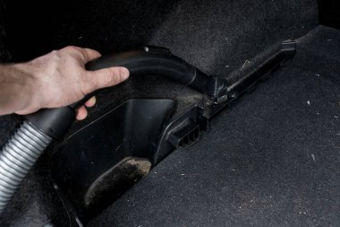 Bir el, arabanın paspasını süpürür, yeni bir iç mekan için toz ve enkazı temizler. Araç bakımı, temizlik ve otomotiv hijyeni için ideal..