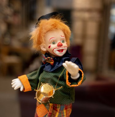 A very colorful clown doll with orange hair and a red nose