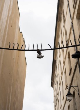 a shoe hanging from a fence that crosses a street