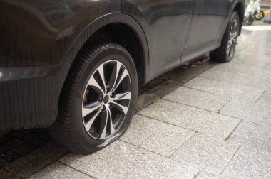 A car parked on the sidewalk with both tires flat. Bandalism in the streets.
