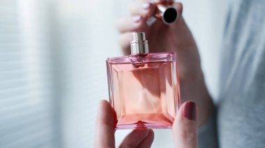 Kadın elinin içindeki parfüm şişesi arka plandaki aydınlatma odasının iç yüzüne karşı. Eau de tuvalet, eau de parfum, güzellik konsepti.