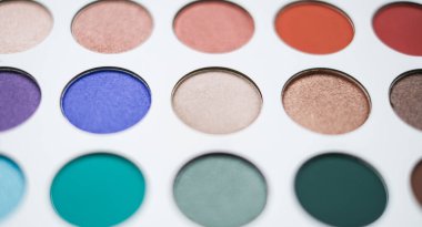 Selective focus of eyeshadow palette with various colors in pearly and matte closeup.