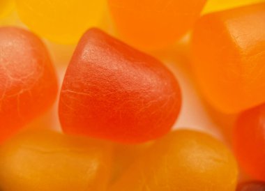 Beyaz arka planda turuncu ve sarı multivitamin sakızlarının yakın çekim dokusu. Sağlıklı yaşam tarzı kavramı.