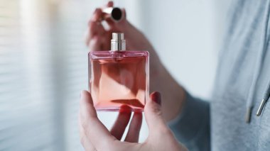 Kadın elinin içindeki parfüm şişesi arka plandaki aydınlatma odasının iç yüzüne karşı. Eau de tuvalet, eau de parfum, güzellik konsepti.