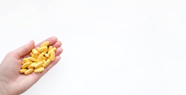 Beyaz arka planda kadın elinde bulunan sarı multivitamin haplarının yakın çekim dokusu. Sağlıklı yaşam tarzı kavramı.