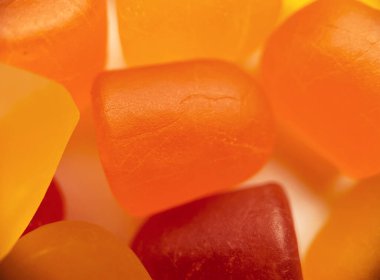 Beyaz arka planda turuncu ve sarı multivitamin sakızlarının yakın çekim dokusu. Sağlıklı yaşam tarzı kavramı.