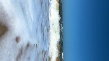 Güneşli bir günde dalgalı deniz manzarası. Eğlence ve turizm konsepti. Dikey video