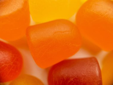 Beyaz arka planda turuncu ve sarı multivitamin sakızlarının yakın çekim dokusu. Sağlıklı yaşam tarzı kavramı.
