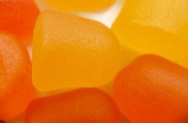 Beyaz arka planda turuncu ve sarı multivitamin sakızlarının yakın çekim dokusu. Sağlıklı yaşam tarzı kavramı.