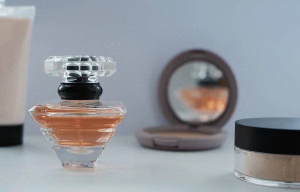 A perfume bottle surrounded by beauty products, powder, lotion. Eau de toilette, eau de parfum, beauty concept.