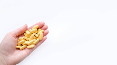 Beyaz arka planda kadın elinde bulunan sarı multivitamin haplarının yakın çekim dokusu. Sağlıklı yaşam tarzı kavramı.