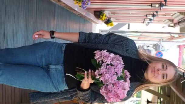 금발의 아름다운 코카서스 하이드라게아 꽃다발 도시의 풍경을 배경으로 선글라스를 — 비디오