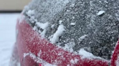 Karla kaplı ve buzlu camları kardan fırçalanmış bir arabanın yakın çekimi.