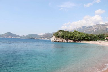 Arkasında gök mavisi su ve dağlar olan deniz manzarası..