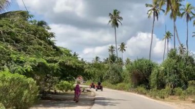 Güneşli bir günde tozlu Afrika yollarında palmiye ağacı geçidi boyunca dört tekerli bisiklet..