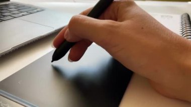Grafik tableti için kalemle çalışan bir elin yakın çekimi.