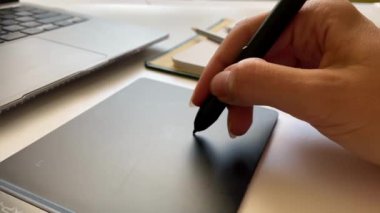 Grafik tableti için kalemle çalışan bir elin yakın çekimi.
