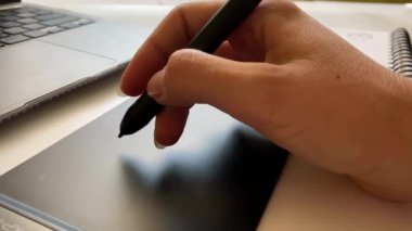 Grafik tableti için kalemle çalışan bir elin yakın çekimi.
