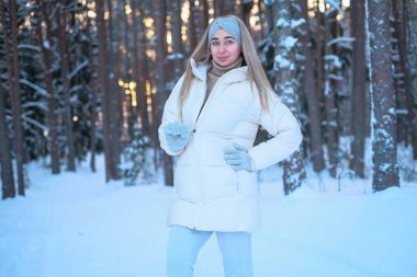 Beyaz ceketli ve şapkalı bir kadın karın üzerinde duruyor..