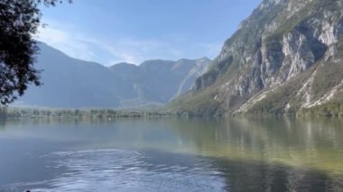 Arkasında dağlar olan güzel bir göl. Su sakin ve berrak, uzaktaki dağları yansıtıyor. Huzurlu ve huzurlu bir sahne.