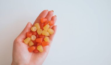 Çeşitli renklerde multivitamin sakızları tutan bir el..