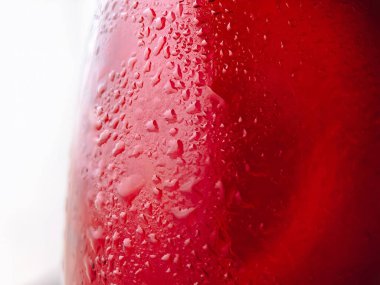 Kırmızı cam yüzeydeki su damlacıklarının makro görüntüsü. Canlandırıcı ve yüksek kontrastlı soyut bir görüntü içki, su ve yaz temalı tasarımlar için idealdir..