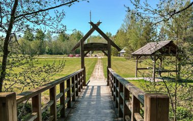 Huzurlu bir kırsal alanda ahşap bir kapıya çıkan manzaralı ahşap köprü. Yürüyüş, turizm ve açık hava keşfi için mükemmel bir ortam..