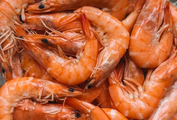 Canlı portakal kabukları ve detaylı dokuları olan taze, pişmiş karides yığınının yakın çekimi. Deniz ürünleri doğal, üst üste binen bir düzende sıralanmıştır, aşçılık, deniz ürünleri pazarı veya menü için idealdir.