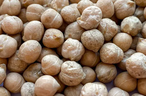 Detaylı doku ve doğal toprak tonlarını gösteren kuru bezelyelerin makro yakın çekimi. Bu baklagiller genellikle sağlıklı yemek pişirme, bitki temelli diyet ve vegan yemek tariflerinde kullanılır.