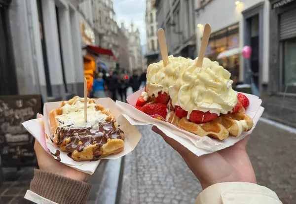Brüksel 'in büyüleyici sokaklarını keşfederken üzerinde krema, taze çilek ve çikolata sosu olan iki lezzetli Belçika waffle' ının tadını çıkarıyorum. Şehir yürüyüşü için harika bir ikramdı..