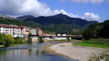 İspanya 'nın Asturias kentindeki Arriondas kasabasının içinden sakin bir nehrin aktığı pitoresk bir videosu. Kamera, geleneksel mimari astarlı bir dizi büyüleyici binayı yakalar.