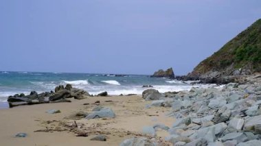 İspanya, Asturias 'ta geniş açılı, parlak bir kıyı manzarası, açık, mavi bir gökyüzünün turkuaz okyanus ufkuyla buluşması. Ön planda engebeli, pürüzlü, karanlık bir kaya var.