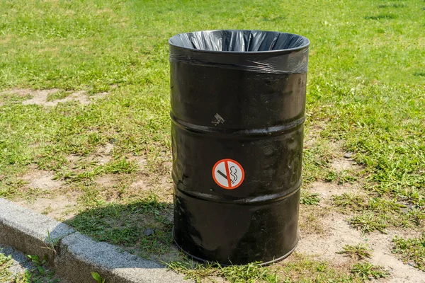 Trash can with no smoking sign on it on street