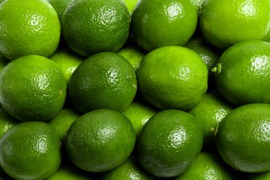 Parlak yeşil limonların arka planı. Tazelik, sululuk ve turunçgillerin doğal dokusu. 