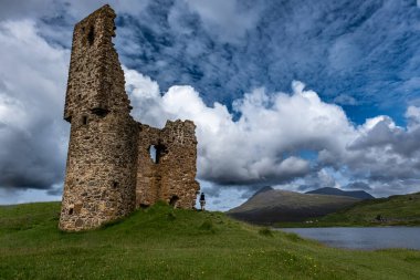Ardvreck Kalesi 'nin kalıntıları Loch Assynt, İskoçya' da MacLeod Klanı 'na ait kaleler. Yalnız turist yürüyor